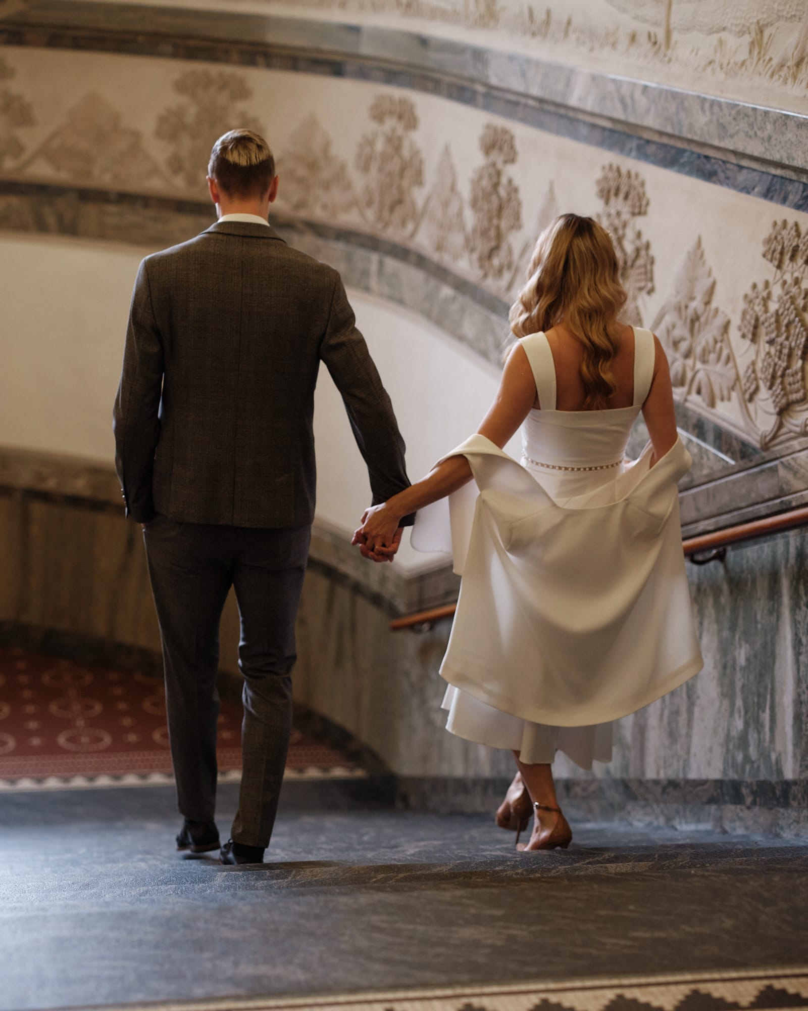 Wedding couple walking down the historic City Hall staircase