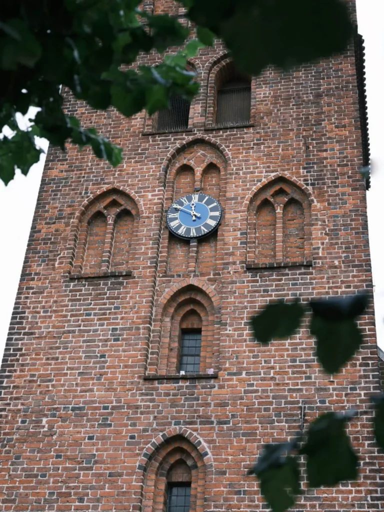 The historic clock tower of Lyngby Church, with its distinctive brickwork and arched windows.