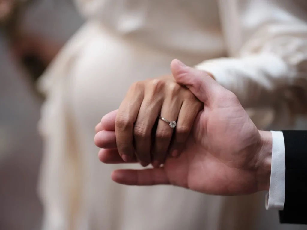 Newlyweds holding hands at Copenhagen City Hall, showcasing a diamond ring, by a wedding photographer.