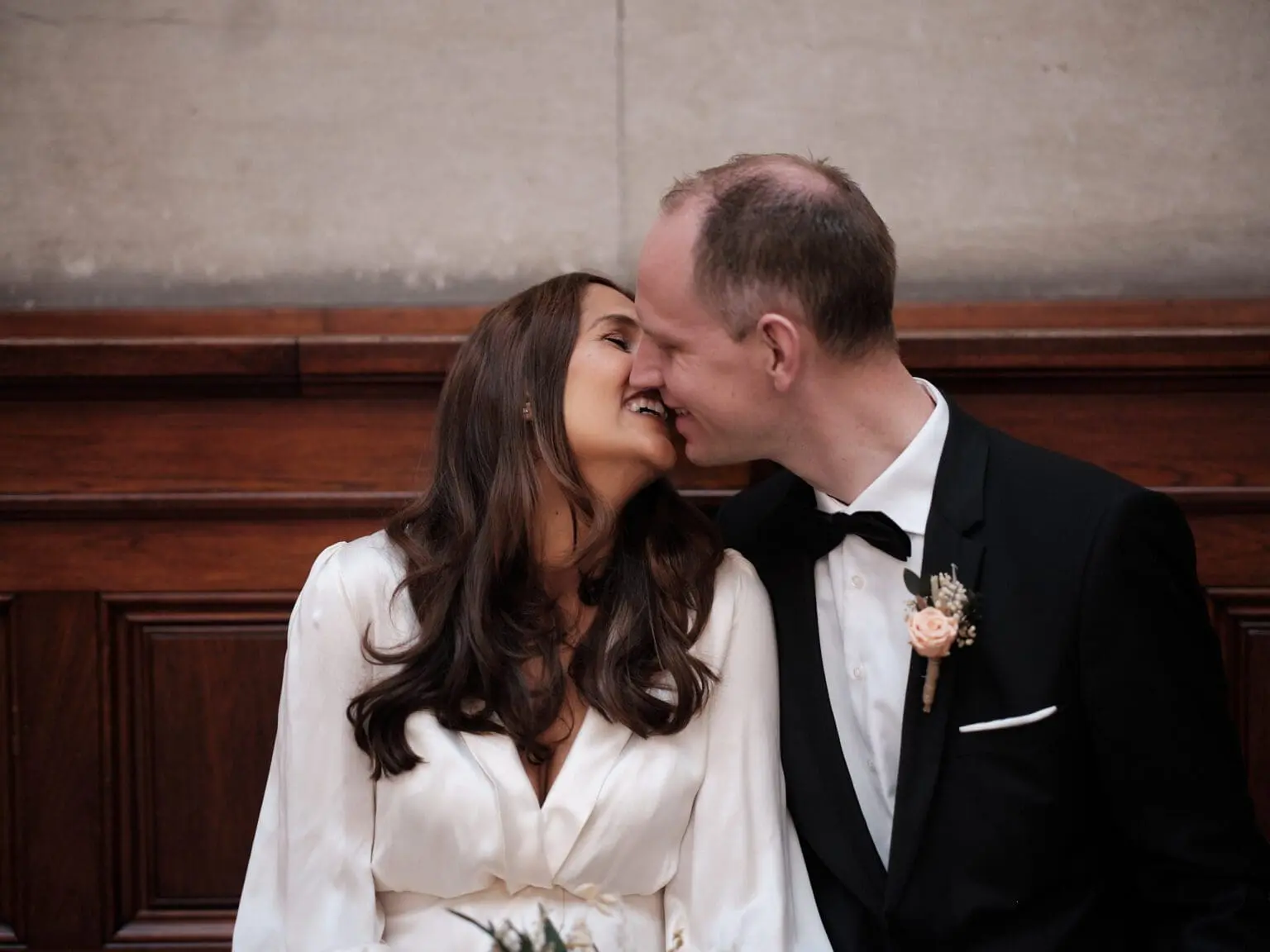 Laughing couple in a tender nose-to-nose moment at Copenhagen City Hall, captured by their wedding photographer.