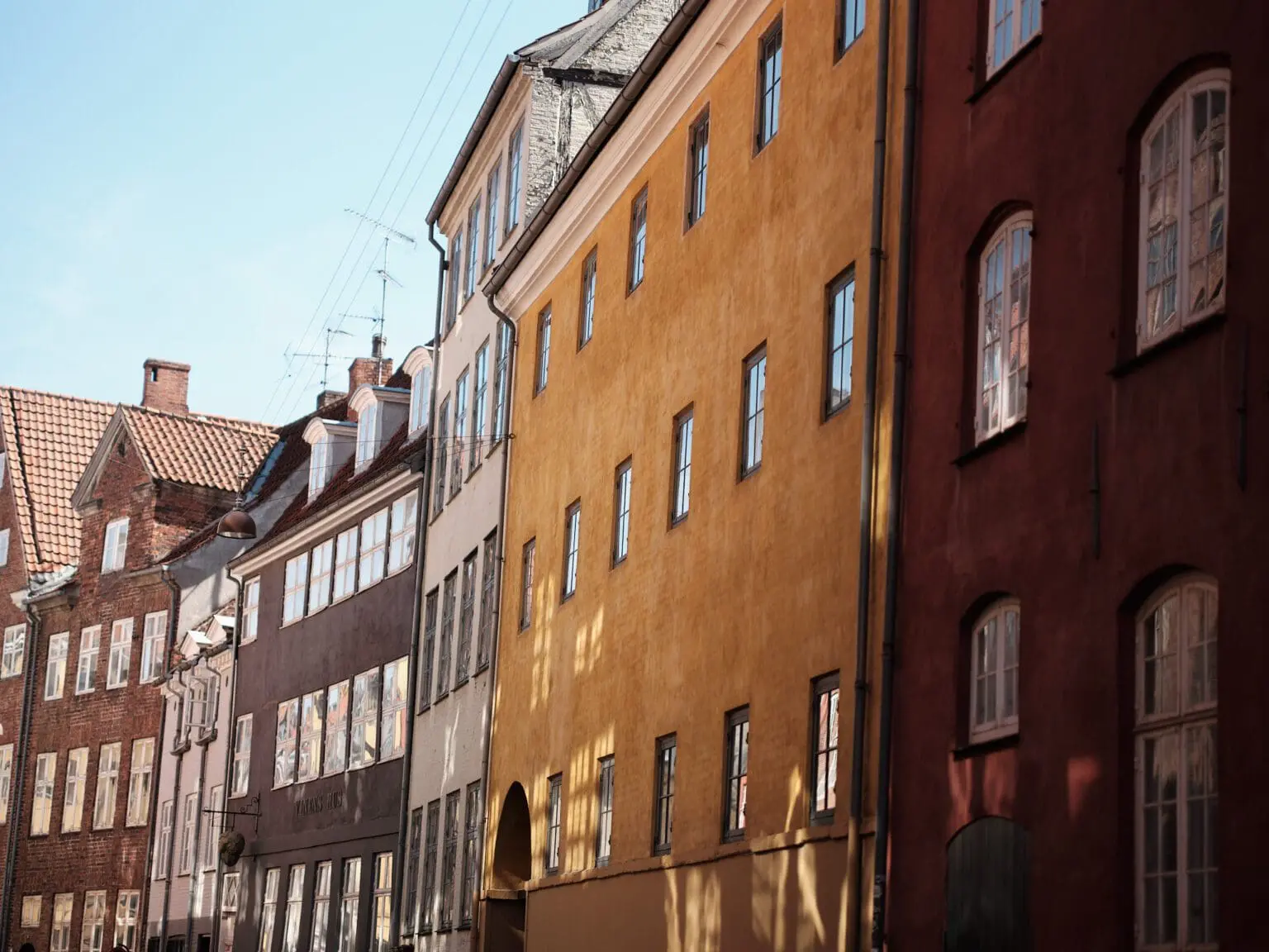 Warm sunlight on the colorful facades of Magstræde, one of the oldest streets in Copenhagen's Old Town.