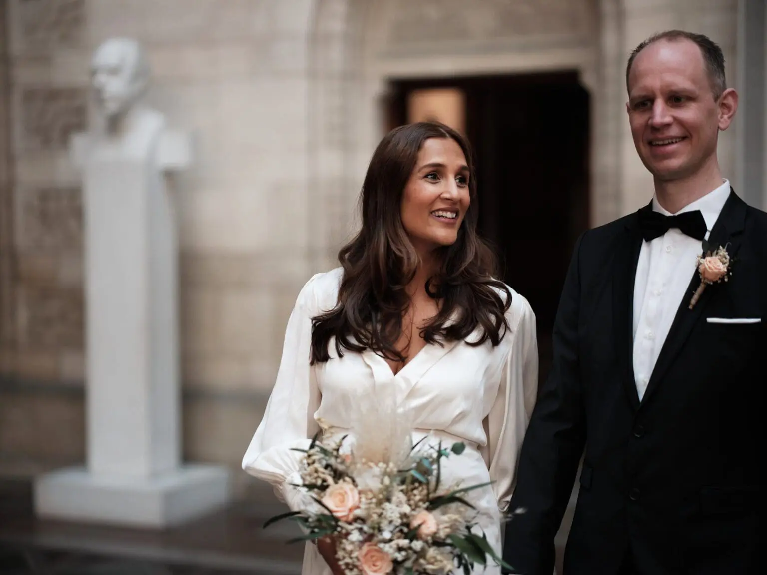 Wedding couple with a serene backdrop of a statue at Copenhagen City Hall, image by Nordic Wedding Photography