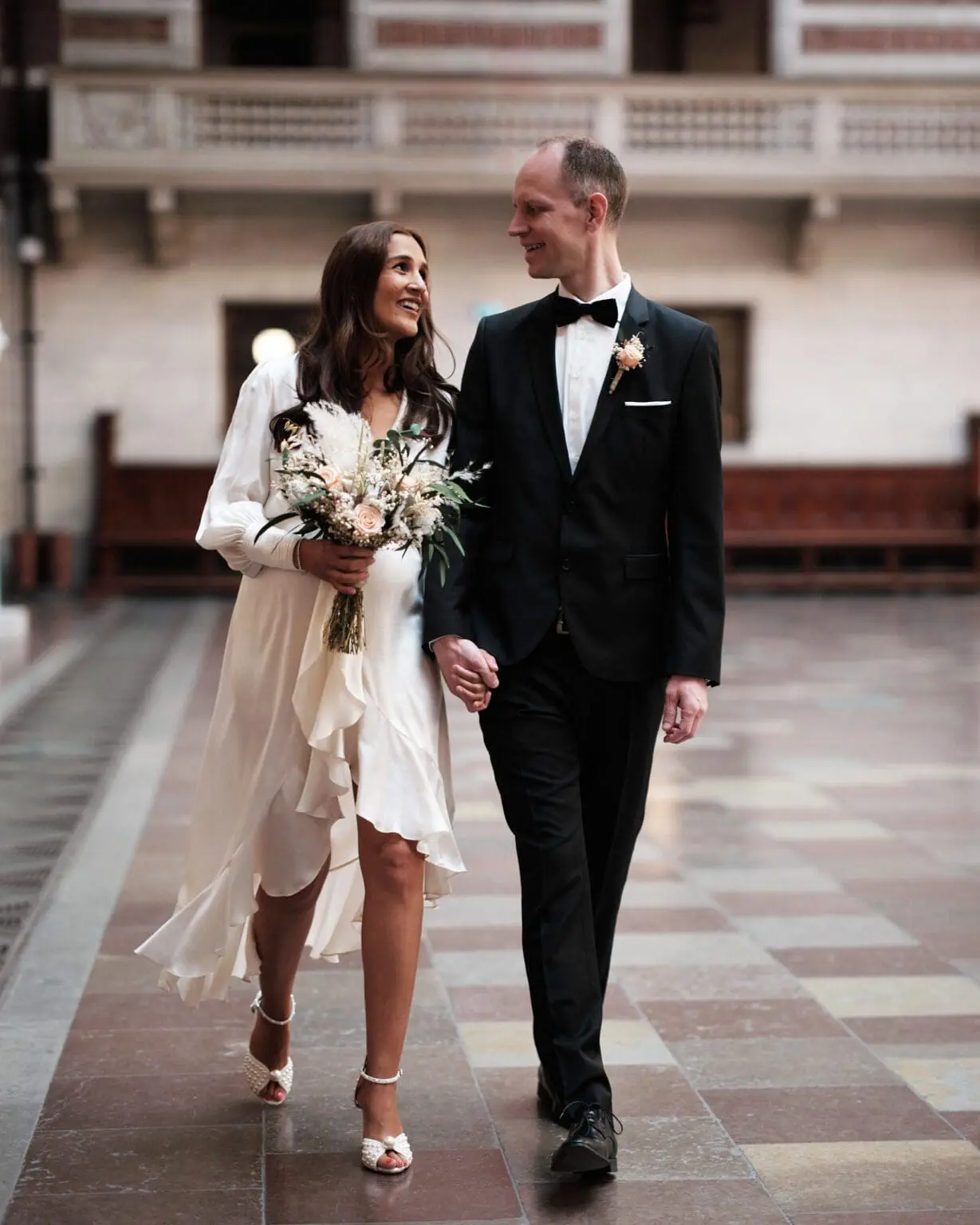 Bride and groom walking hand in hand through Copenhagen City Hall, as captured by Nordic Wedding Photography.