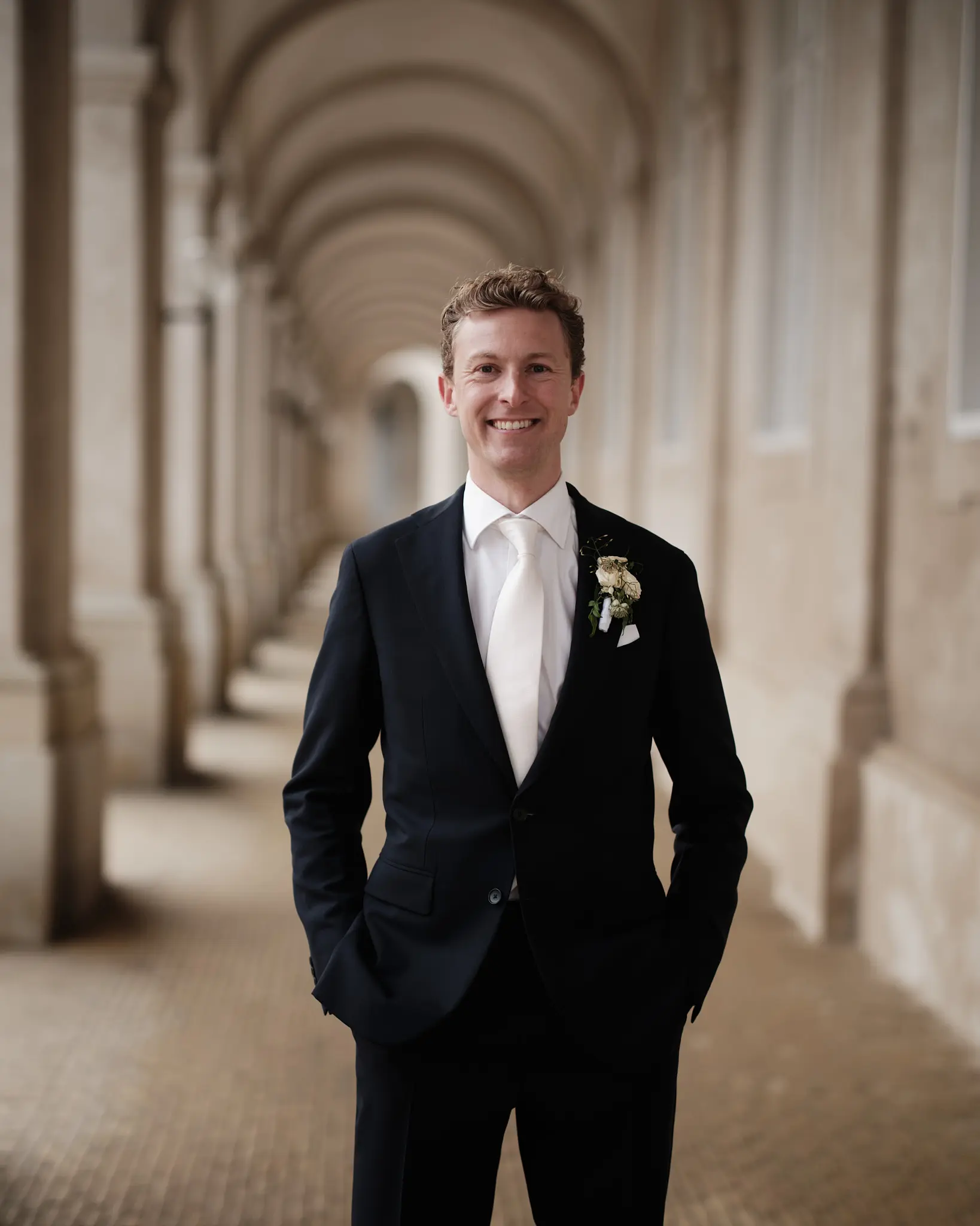 Glad gom i blåt jakkesæt smiler forventningsfuldt på Christiansborg Slot - Nordic Wedding