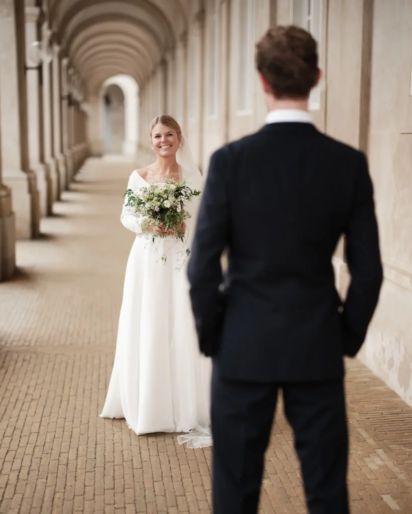 Brud smiler til gommen i gangen ved Christiansborg Slot, København - Nordic Wedding